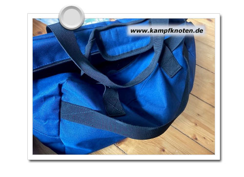 blaue Reisetasche mit labbrigem Riemen für einen Rollkoffergriff